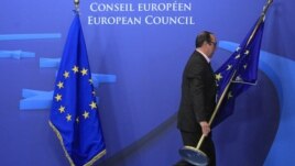 Belgium -- An employee at the EU council adjusts European Union flags at the entrance of the council headquarters for an European Union leaders summit discussing the European Union's long-term budget in Brussels, 22Nov2012