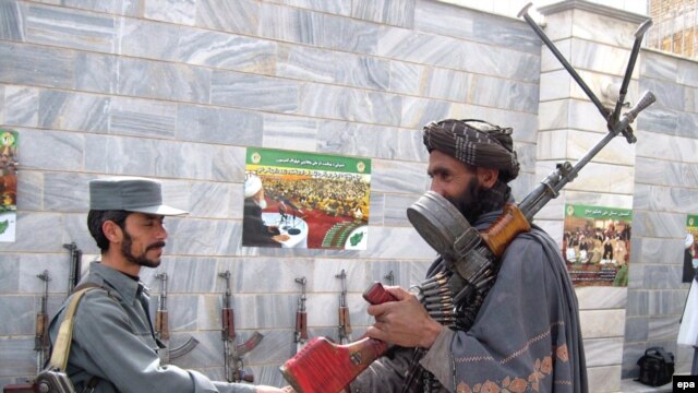 A former Taliban fighter (right) shakes hands with a policemen in Herat as he and other militants attend a ceremony to surrender under a U.S.-backed Afghan government amnesty scheme.