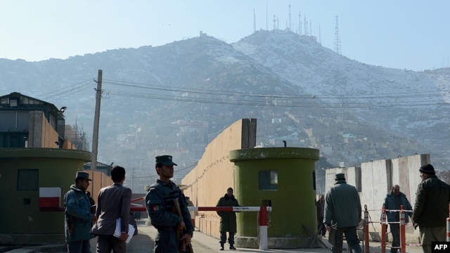 Afghan policemen stand guard at the entrance to police headquarters on December 24 in Kabul where a female police officer shot dead a foreign civilian adviser.