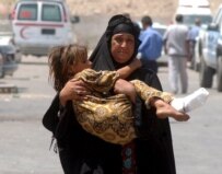An Iraqi woman carries her injured daughter from the site of a bomb attack in Baghdad (file photo) (epa)