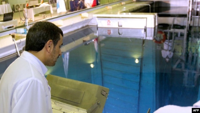 Iranian President Mahmud Ahmadinejad looks at a metal-encased rod with enriched nuclear fuel as it is inserted into a reactor in Tehran. (file photo)