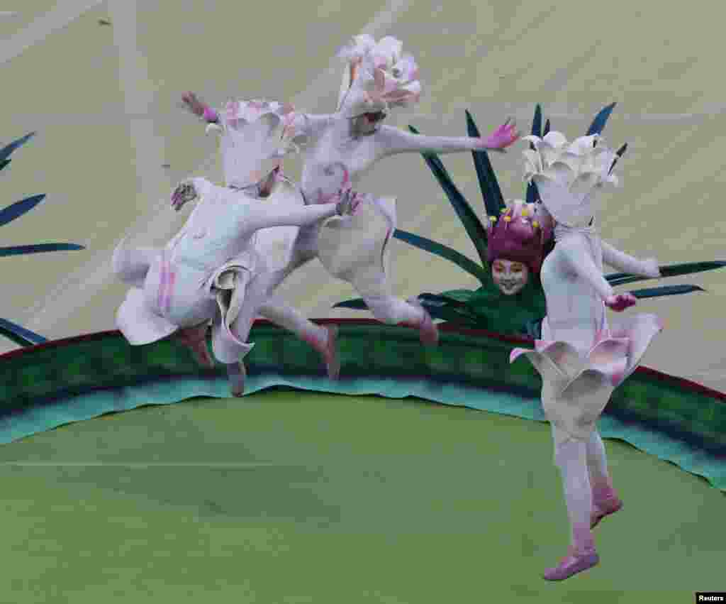 Performers bounce on a trampoline.