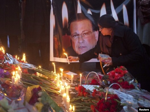 A woman lights a candle next to an image of the governor of Punjab, Salman Taseer, during a candlelight vigil near the site of his assassination in Islamabad.