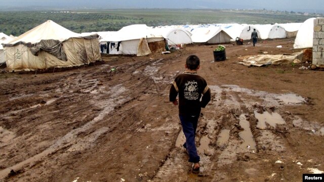 A refugee boy walks through mud at a refugee camp in Atimeh, on the Syrian-Turkish border of the Idlib Governorate.