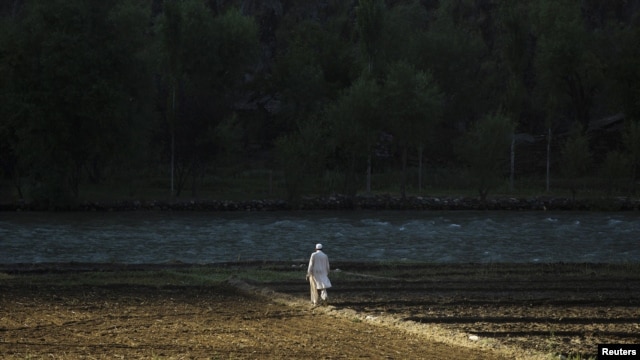 The early morning sun hits a man as he walks across a field near the village of Qandaro in the Pech River Valley of Kunar Province on July 2.