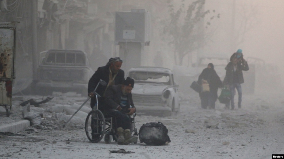 A man in a wheelchair flees with others into the remaining rebel-held areas of Aleppo on December 9.