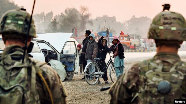 Afghan children gesture at U.S. soldiers as they stand guard near an Afghan security checkpoint in Nangarhar Province. (file photo)