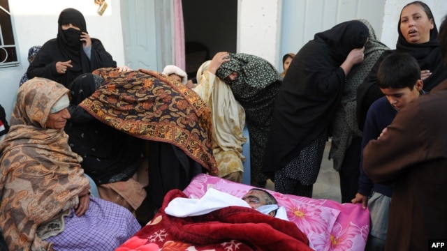Shi'a mourn beside the body of a blast victim following the overnight suicide bomb attack on a Shi'ite procession in Rawalpindi on November 21-22.