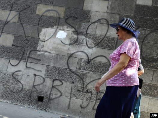 A woman in Belgrade walks past graffiti reading 'Kosovo is the heart of Serbia.'