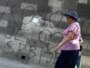 A woman in Belgrade walks past graffiti reading "Kosovo is the heart of Serbia."