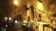 Workers stand beside machinery in a tunnel in the Kumtor mine.