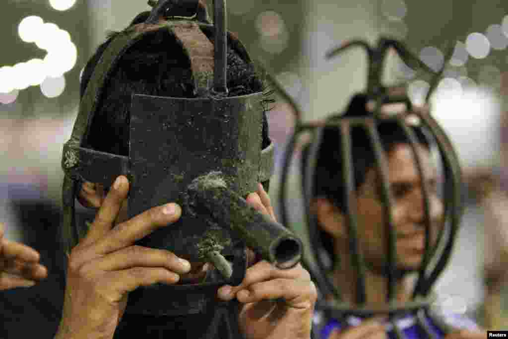 Visitors try on metal masks that were used as torture devices by the regime of Iraq's ousted leader Saddam Hussein at an exhibition at the Martyrs Monument in Baghdad. (Reuters/Thaier al-Sudani)
