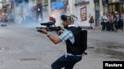 A plainclothes police officer fires plastic paintball gun pellets to disperse protesters in central Istanbul earlier this month.