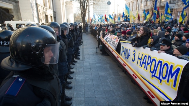 Шерушілер парламент ғимаратын күзеткен полиция жасағына қарсы "Парламент халықпен бірге" деген жазуы бар плакаттар алып шықты. Киеве, 3 желтоқсан 2013 жыл. 