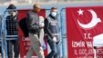 A migrant is escorted by a Turkish police officer walking past a banner reading: "Migration directorate of the Izmir Governor" as they arrive by ferry from the Greek island of Lesbos at the Dikili harbor in Izmir on April 4.