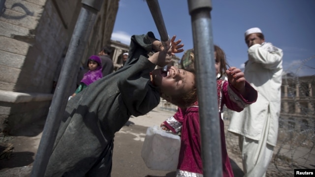 A Kuchi boy tries to drink water in front of the ruins of Darul Aman palace in Kabul.