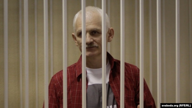 Belarusian human rights activist Ales Byalyatski stands in a guarded cage during his trial for tax evasion in Minsk.