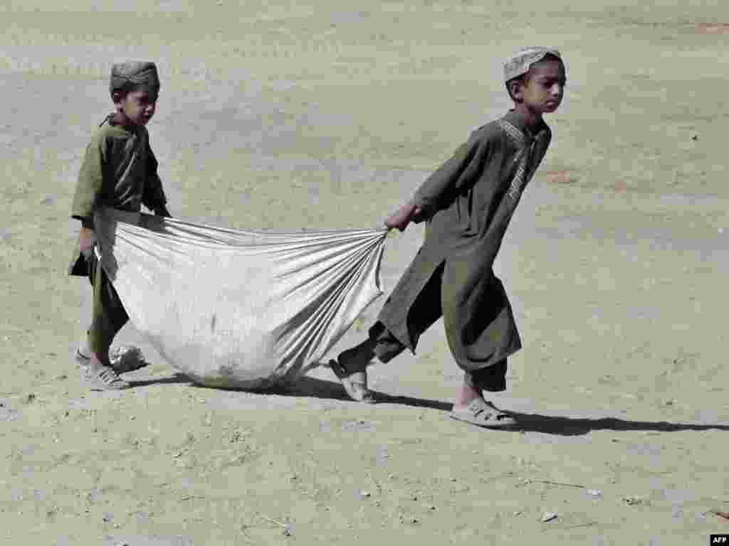 Afghan boys pick up trash around a bazaar outside a U.S. Marines combat outpost in Helmand Province.