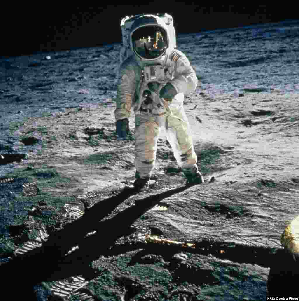 Astronaut Buzz Aldrin walks on the moon’s Sea of Tranquility, his visor reflecting Neil Armstrong and the lunar module "Eagle." The Apollo 11 astronauts carried the National Geographic Society flag with them on their journey to the moon.