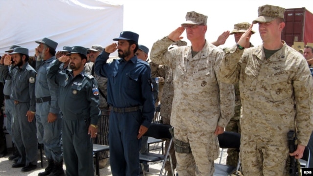 Afghan police and U.S. Marines salute during a ceremony marking conclusion of the Afghans' training.