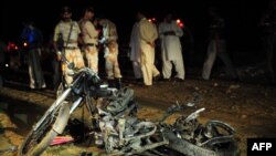 Officers stand beside the wreckage of a motorbike after a bomb exploded in Karachi earlier this month, part of a wave of bombings that has struck Pakistani cities.