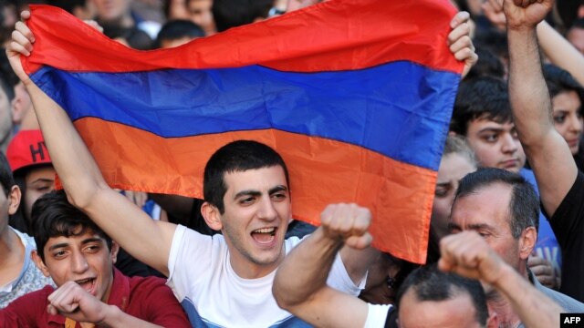 A demonstrator holds an Armenian flag as others shout slogans during a protest against an increase on electricity prices in Yerevan on June 25.