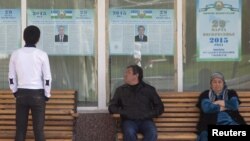 Люди смотрят на предвыборные плакаты кандидатов в президенты. Ташкент, 26 марта 2015 года.