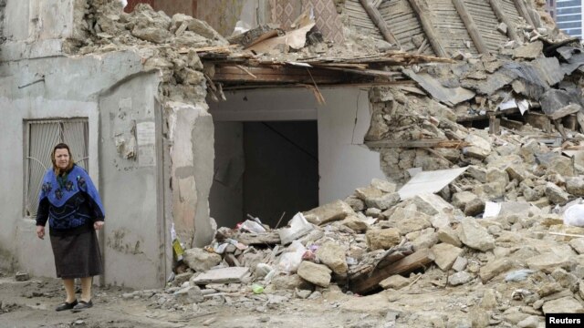 A woman stands near a demolished house in Baku. Critics say the government has trampled on people's rights in razing homes for the Crystal Hall..