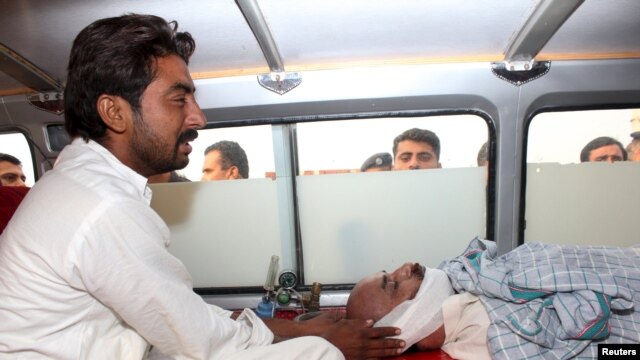 The brother of Ansar Iqbal sits in an ambulance next his brother's bodyafter his execution.