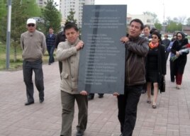 Гражданские активисты несут мемориальную плиту в память погибших в Жанаозене. Астана, 28 апреля 2012 года.