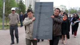 Астанада оппозиция белсенділері мемлекеттік рәміздер алаңында Жаңаөзен құрбандарының аты жазылған қара мрамор тақтаны әкеле жатыр. Астана, 28 сәуір 2012 жыл.