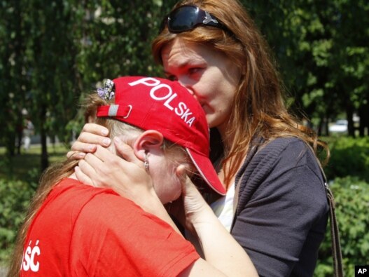 Aksana, wife of Andrzej Poczobut, comforts her daughter Yana as they stand in front of the court building where Paczobut is on trial in Hrodna.