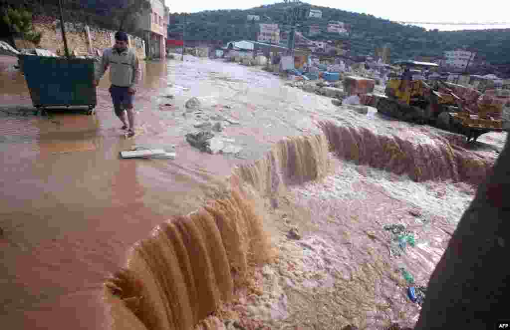 A man walks through water in the village of Qabatiya in the Israeli occupied West Bank near the northern city of Jenin as rainstorms and snow hit the region. (AFP/Saif Dahlah)