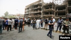 Сотрудники сил безопасности Ирака и местные жители на месте атаки в районе Каррада в Багдаде. 4 июля 2016 года.