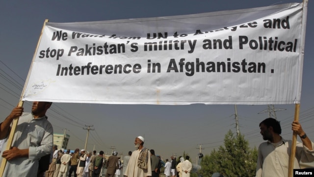 Men hold a banner aloft during a demonstration in Kabul against crossborder shelling attacks on August 30.