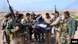 Iraqi Kurdish Peshmerga soldiers hold a flag belonging to the Islamic State militant group after they regained control of an area west of Kirkuk in March 2015.