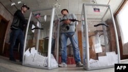 Armed pro-Russian activists stand guard near ballot boxes during the referendum called by pro-Russian rebels to split from the rest of Ukraine on May 11 in Donetsk.