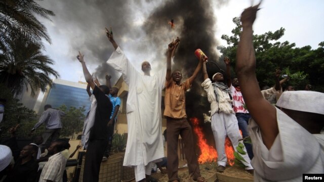 Sudanese demonstrators stand in front of the burning German Embassy in Khartoum after Friday Prayers on September 14.