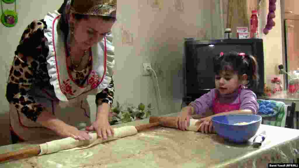 Shahnoz Komilzoda preparing food with her child in their kitchen in Dushanbe