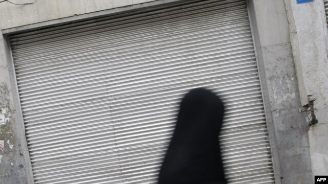 An Iranian woman walks past a closed shop in Tehran. The state of the country's economy is seen as the critical issue in the June 12 presidential election.