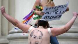 A half-naked Femen activist shows her back, where Belarusian President Alyaksandr Lukashenka is depicted, in front of the KGB headquarters in Minsk on December 19.