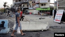 Men walk past at the site of a car bomb attack in Baghdad on August 26.