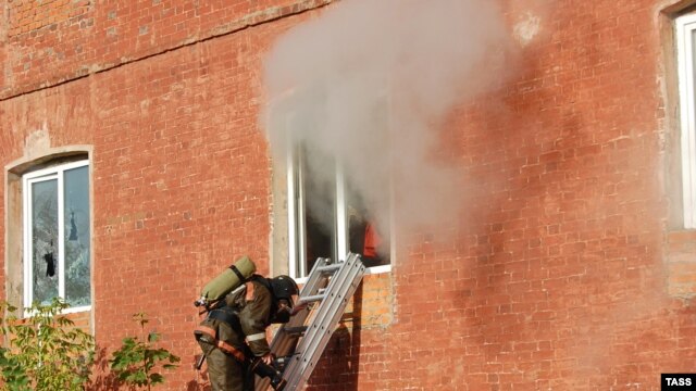 A firefighter stands on a ladder by a window of a garment factory on fire in the town of Yegoryevsk, southeast of Moscow, on September 11.