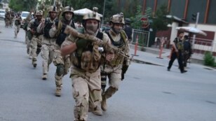Afghan and international special forces run to the site of a clash between Afghan security forces and Taliban fighters in Kabul on May 24. 