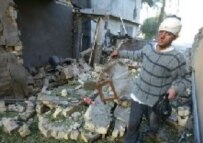 An injured Iraqi man collects belongings from his home after a truck explosion this morning at Qasr Dar al-Salam