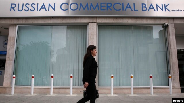 A woman walks past a closed branch of the Russian Commercial Bank in Nicosia, Cyprus. Natalya Orlova says Cyprus's liquidity crisis will become clear when the banks reopen.