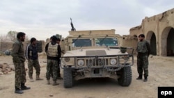 Members of the Afghan security forces stand around a lightly armored vehicle during an operation against Taliban fighters in Helmand Province in December 2015.
