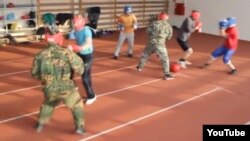 A screen grab from a YouTube video of young men playing "Russian football," which is billed as a hybrid sport between football/rugby and boxing.