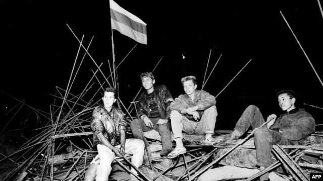Young people sit on a barricade in front of the Russian White House in central Moscow on August 20 1991, during the abortive coup.