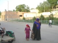 A woman and child on a Chorkuh street (RFE/RL)